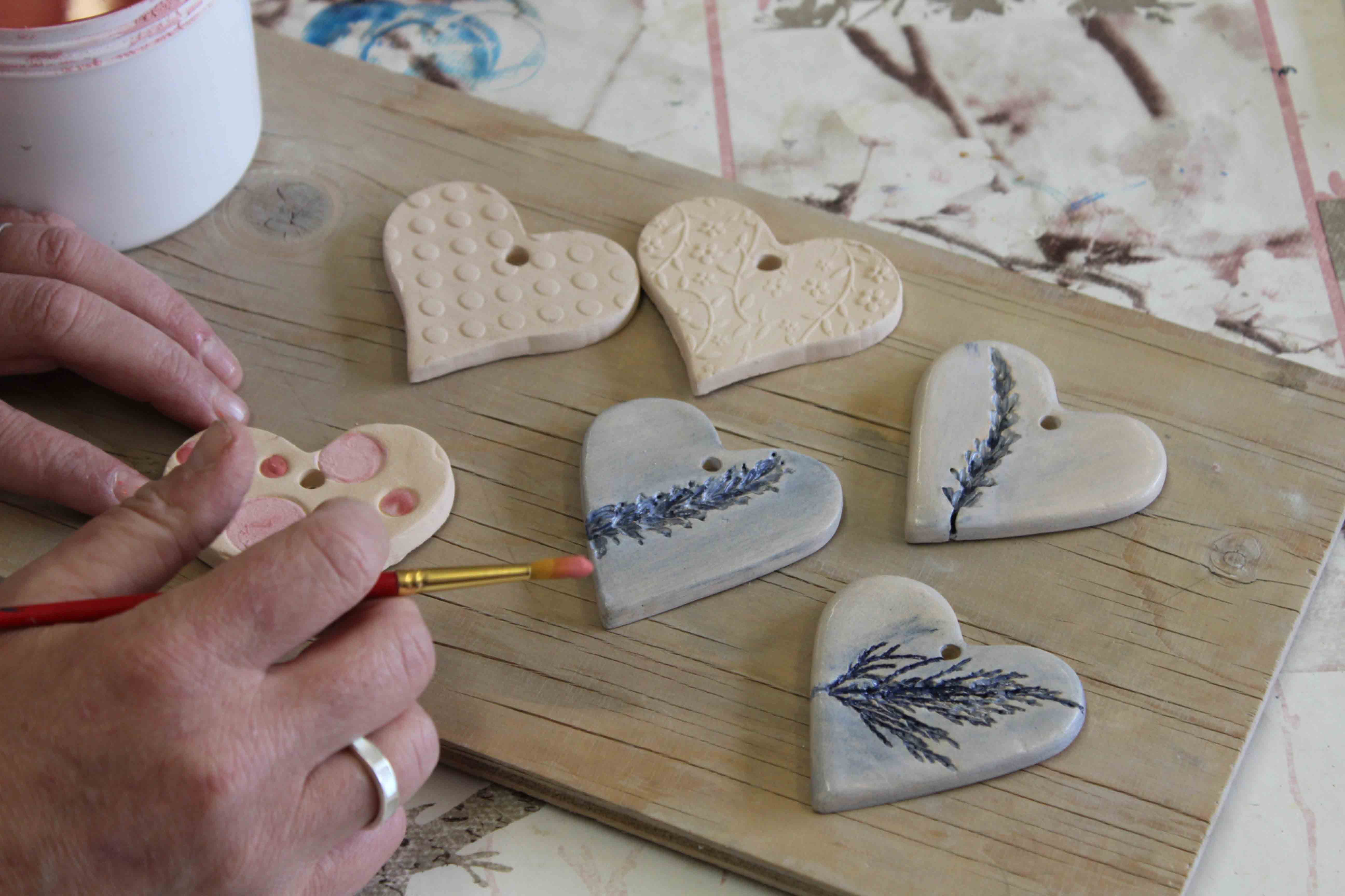 Hands painting hearts made of pottery at Heads Up Somerset, a charity in Wells, Somerset
