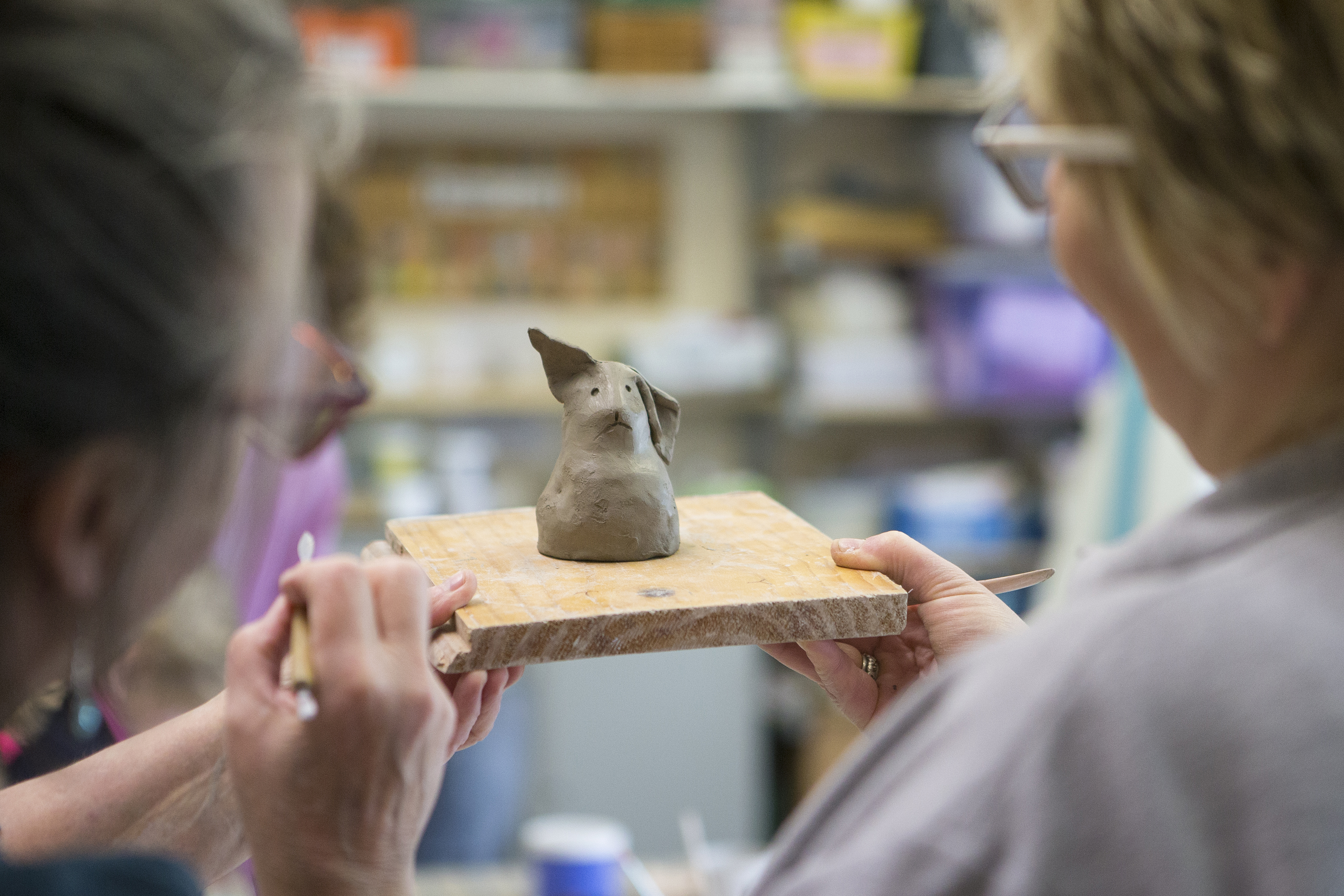 Two people holding onto a pottery figurine at Heads Up Somerset, a mental health and well-being charity in Wells, Somerset