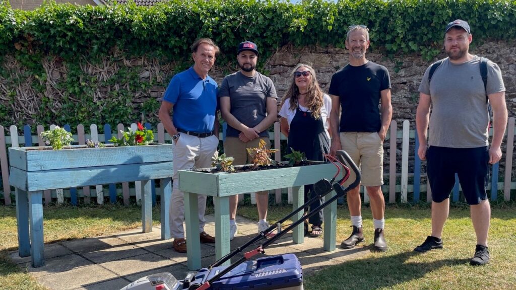 Group of volunteers in the garden with a lawn mower